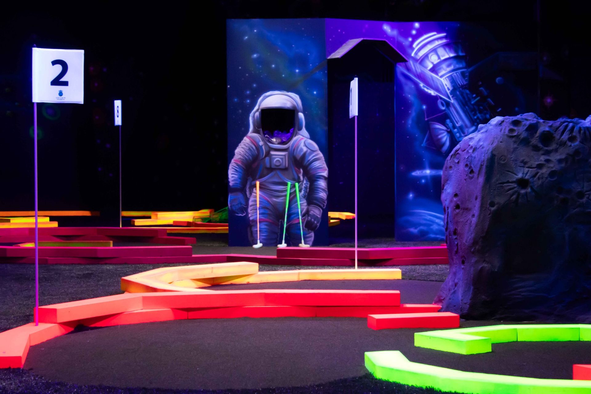 Indoor-Golf-Anlage mit Neon-Akzenten und Astronaut