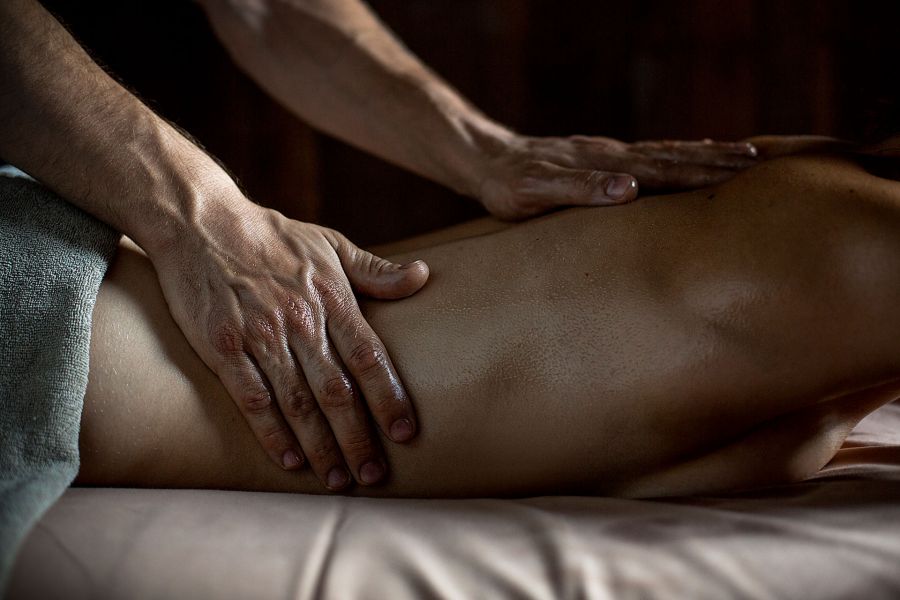 Nahaufnahme eines Rückens, der von zwei Händen eine Massage bekommt.